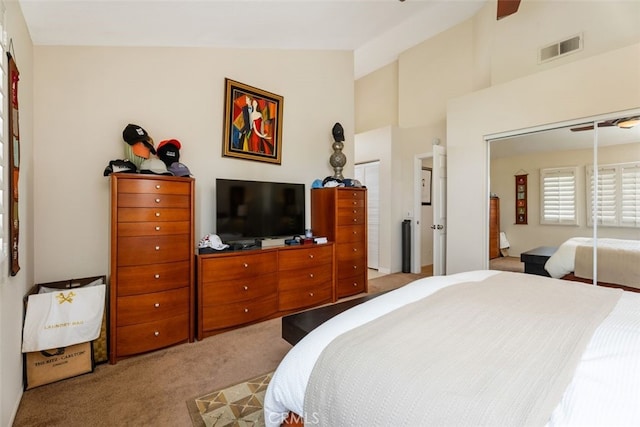 bedroom featuring light carpet, high vaulted ceiling, visible vents, and a closet