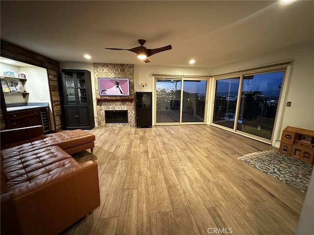 living room featuring light hardwood / wood-style floors, a large fireplace, and ceiling fan