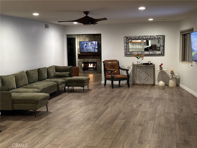 living room with hardwood / wood-style flooring, ceiling fan, and a fireplace