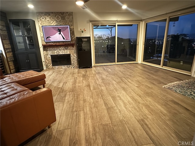 living room with built in shelves, a fireplace, and wood-type flooring