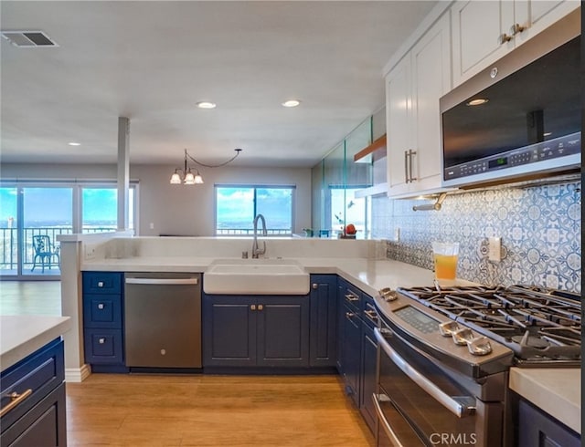 kitchen featuring blue cabinets, sink, kitchen peninsula, stainless steel appliances, and white cabinets