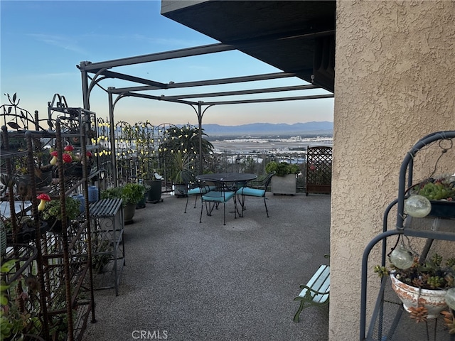 patio terrace at dusk with a mountain view and a pergola