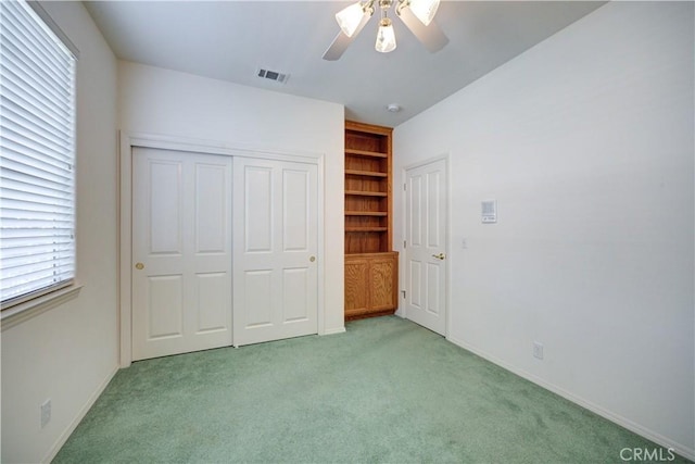 unfurnished bedroom featuring ceiling fan, a closet, and light colored carpet