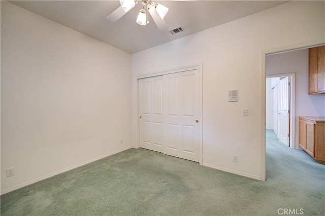 unfurnished bedroom featuring ceiling fan, light carpet, and a closet