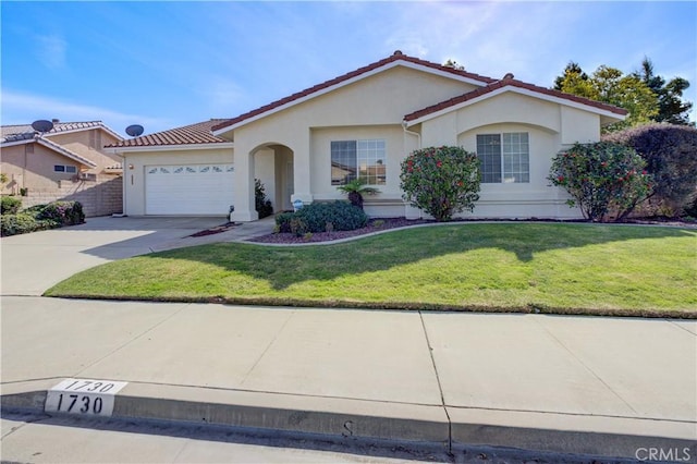 mediterranean / spanish house with a garage, concrete driveway, stucco siding, a tile roof, and a front yard