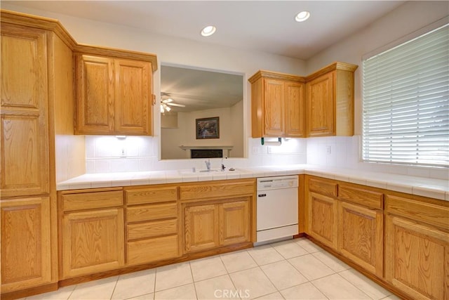 kitchen with tile counters, sink, ceiling fan, and dishwasher