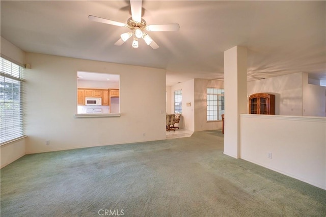 unfurnished living room featuring light carpet and ceiling fan