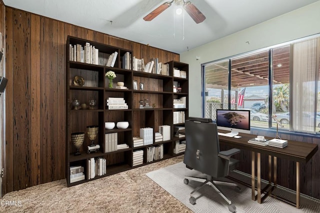 office with ceiling fan and wood walls