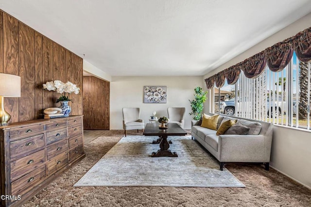 carpeted living room featuring wooden walls