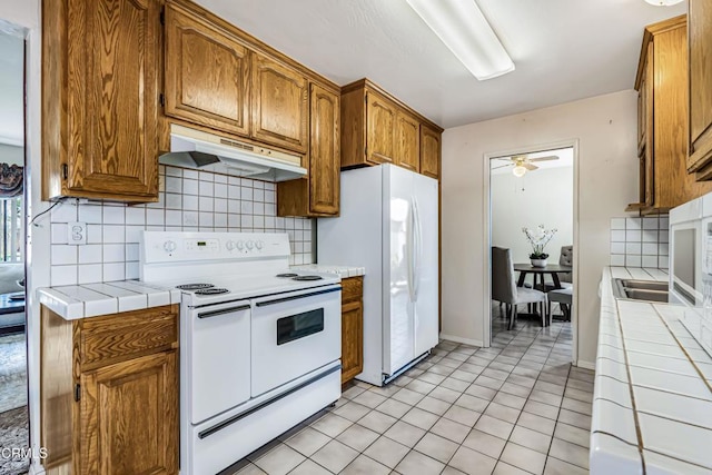 kitchen with backsplash, white appliances, and tile counters