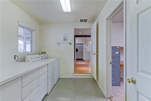 clothes washing area featuring cabinets and washing machine and clothes dryer