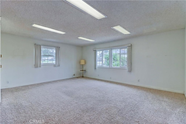 carpeted empty room with a textured ceiling and a wealth of natural light