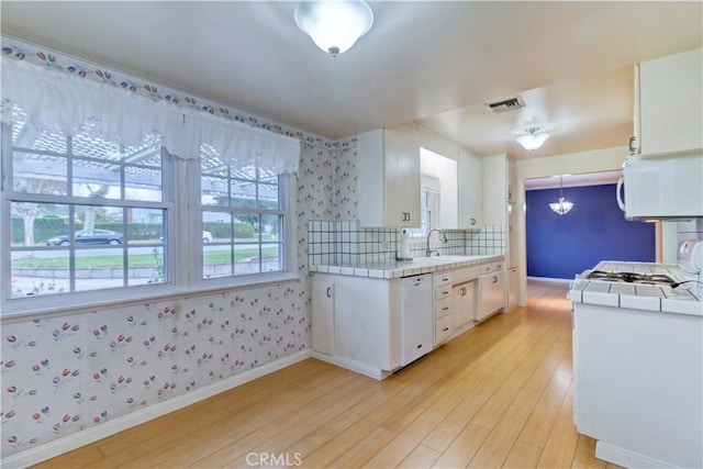 kitchen featuring sink, white appliances, light hardwood / wood-style flooring, white cabinetry, and tile counters