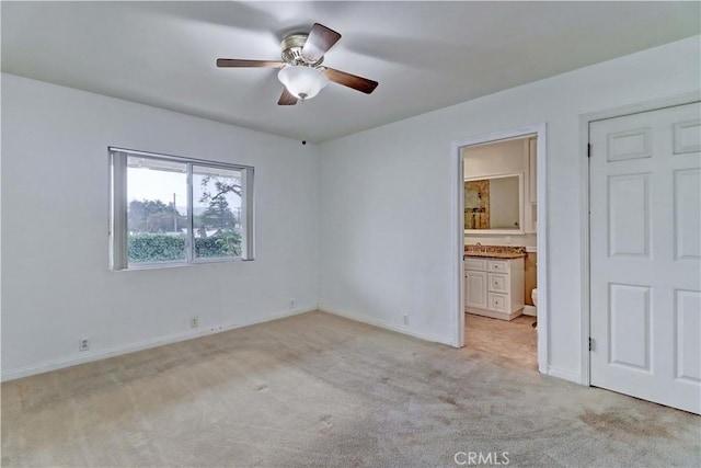 unfurnished bedroom featuring connected bathroom, light carpet, and ceiling fan