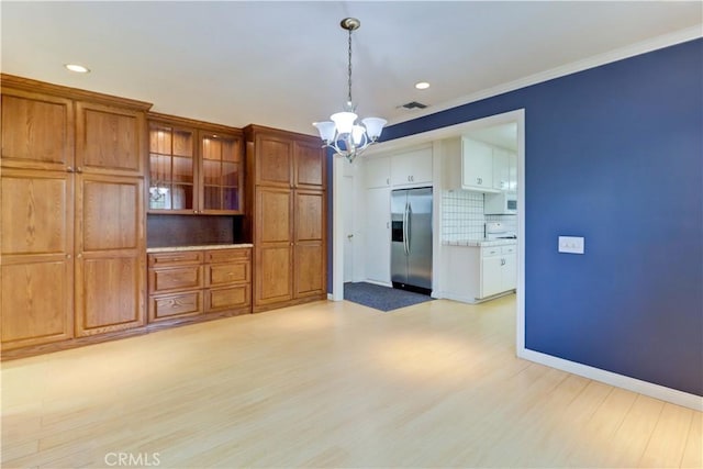 interior space with an inviting chandelier, ornamental molding, and light hardwood / wood-style floors