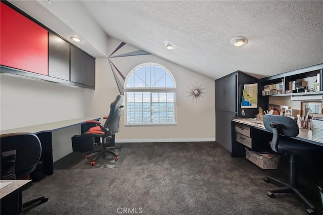 carpeted office space featuring lofted ceiling, built in desk, and a textured ceiling