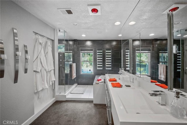 bathroom with vanity, a shower with shower door, and a textured ceiling