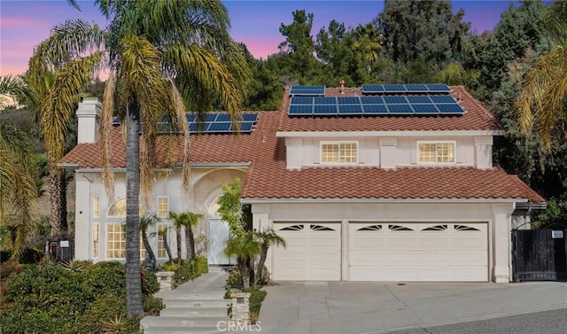 view of front of home featuring a tiled roof, concrete driveway, roof mounted solar panels, stucco siding, and an attached garage