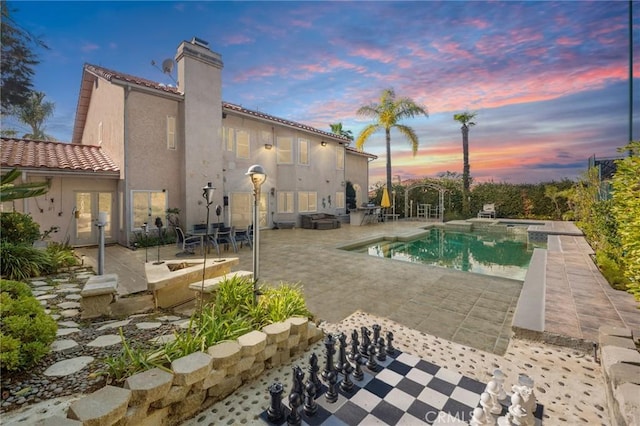 pool at dusk with a patio area