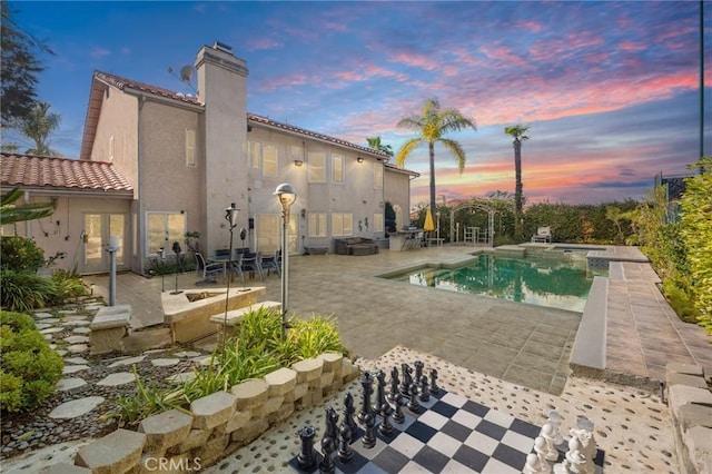 pool at dusk featuring a patio area and an outdoor pool