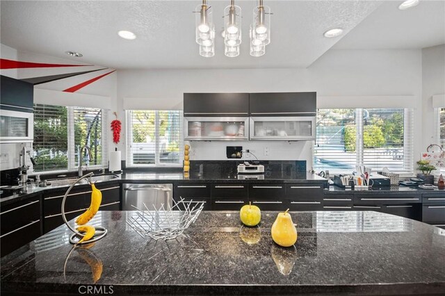 kitchen with a kitchen island, decorative light fixtures, sink, dark stone countertops, and stainless steel dishwasher