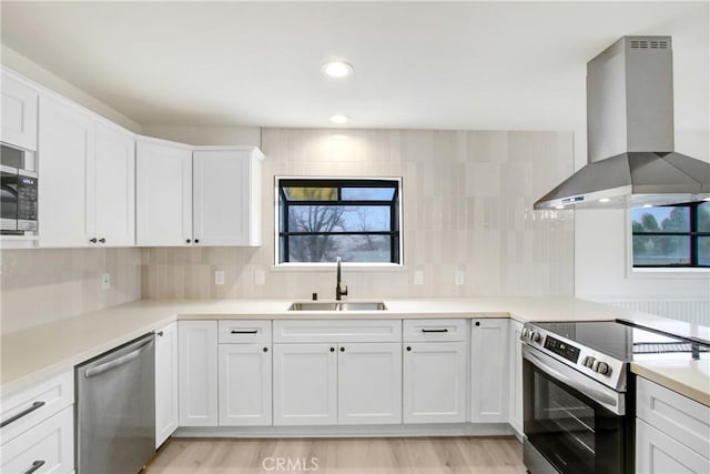 kitchen with white cabinets, stainless steel appliances, sink, and island range hood