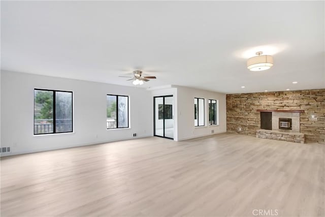 unfurnished living room with ceiling fan, plenty of natural light, a fireplace, and light hardwood / wood-style flooring