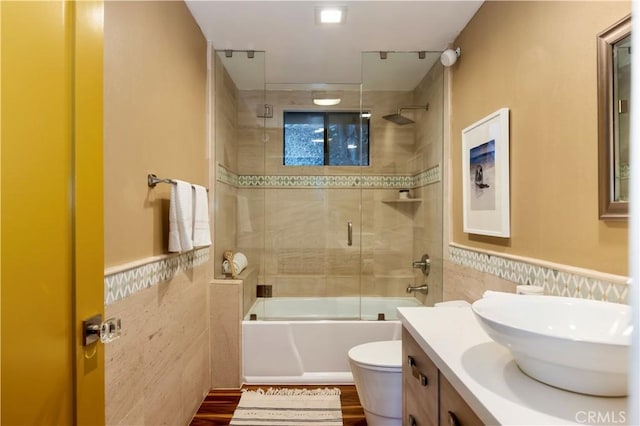 full bathroom featuring tile walls, vanity, enclosed tub / shower combo, and toilet