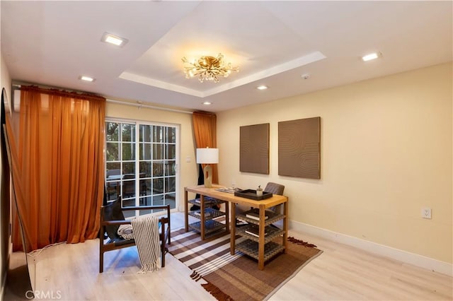 office space with a raised ceiling and light wood-type flooring