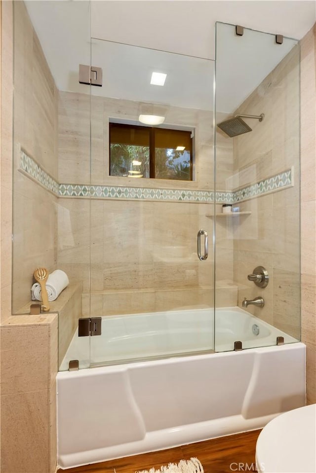 bathroom featuring toilet and combined bath / shower with glass door