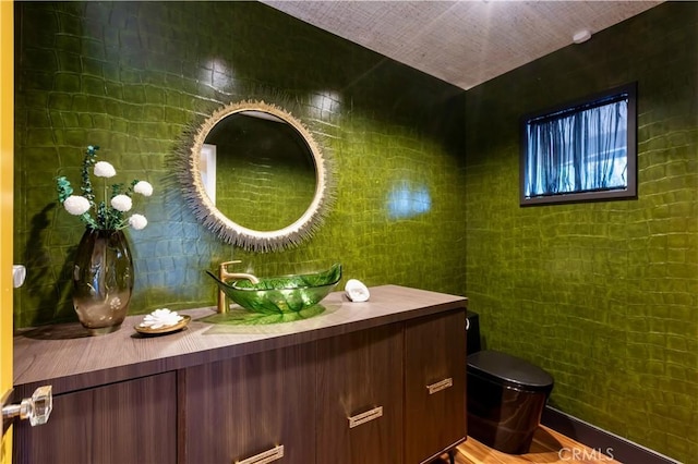 bathroom featuring vanity, tile walls, and toilet