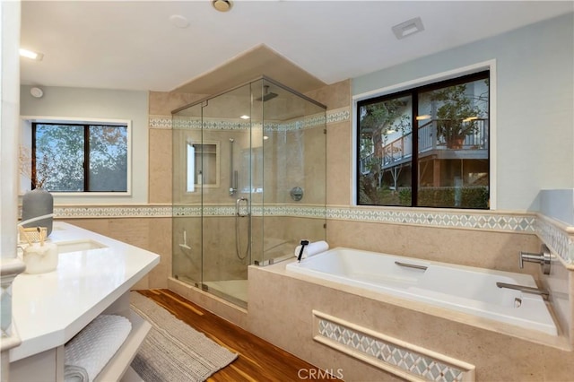 bathroom featuring vanity, independent shower and bath, hardwood / wood-style floors, and tile walls