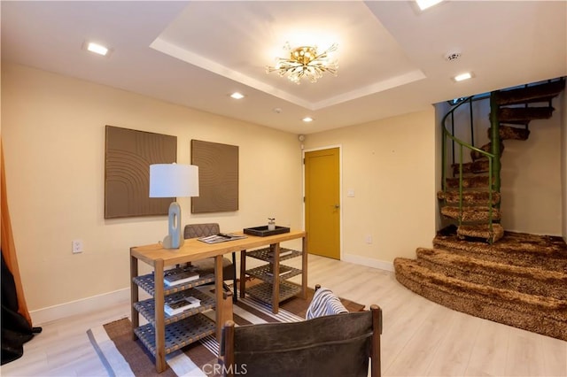 home office with an inviting chandelier, light wood-type flooring, and a tray ceiling