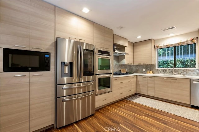 kitchen featuring light brown cabinetry, sink, tasteful backsplash, dark hardwood / wood-style flooring, and stainless steel appliances