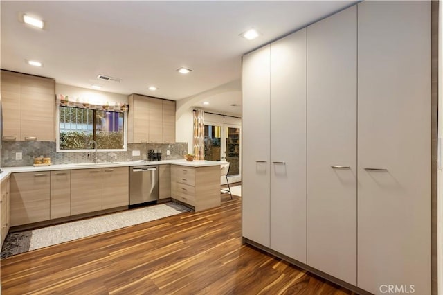 kitchen with dark wood-type flooring, sink, stainless steel dishwasher, kitchen peninsula, and backsplash