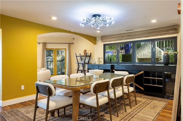 dining space featuring french doors, a healthy amount of sunlight, an inviting chandelier, and hardwood / wood-style floors