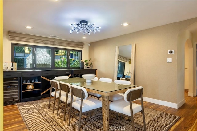 dining room featuring wine cooler, hardwood / wood-style floors, and a notable chandelier