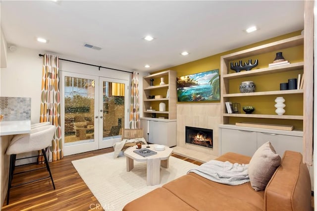 living area with french doors, wood-type flooring, and a fireplace