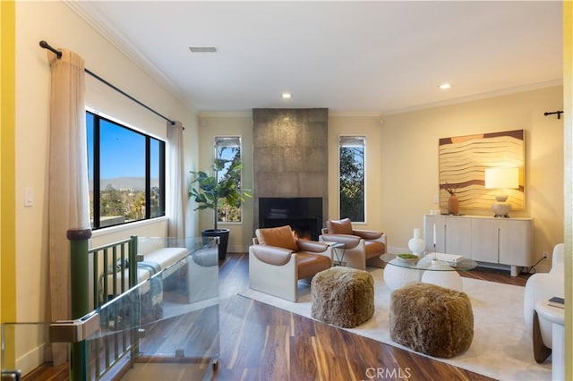 living room with hardwood / wood-style flooring, a fireplace, and crown molding