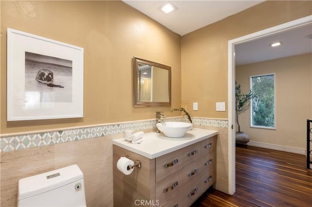 bathroom featuring vanity, wood-type flooring, tile walls, and toilet