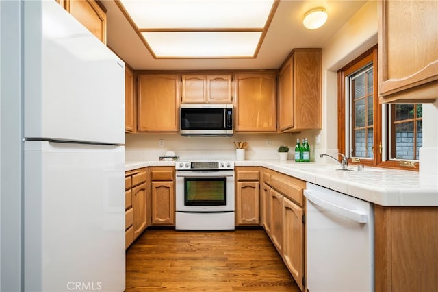 kitchen featuring sink, white appliances, tile countertops, and light wood-type flooring