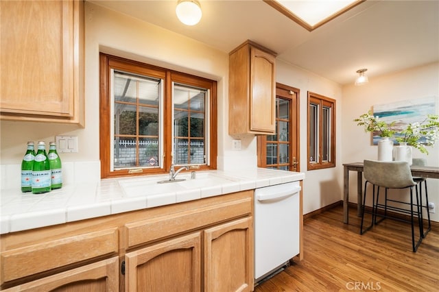 kitchen with dishwasher, sink, tile counters, and light wood-type flooring