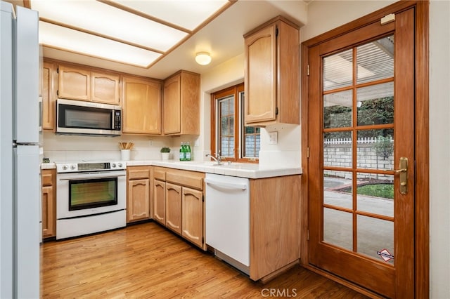 kitchen featuring light brown cabinetry, sink, white appliances, and light hardwood / wood-style floors