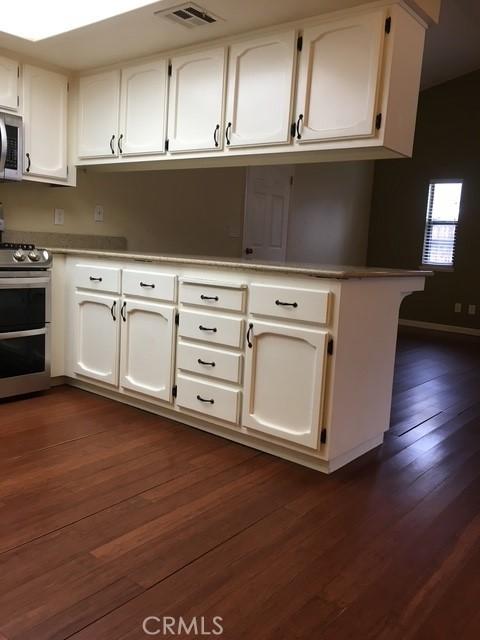 kitchen with stainless steel appliances, white cabinetry, dark hardwood / wood-style flooring, and kitchen peninsula