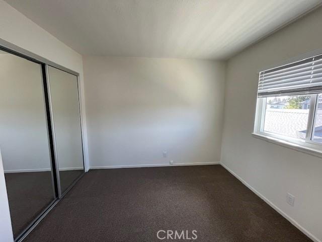 unfurnished bedroom featuring a closet and dark colored carpet