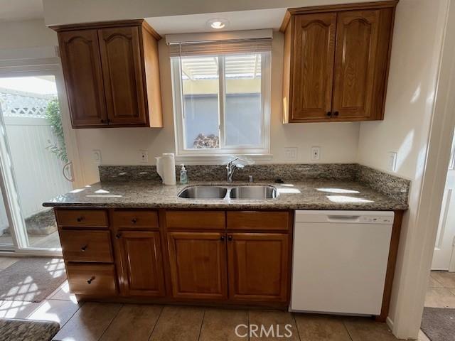 kitchen featuring white dishwasher, sink, and dark stone countertops