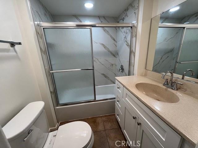 full bathroom featuring shower / bath combination with glass door, tile patterned floors, vanity, and toilet