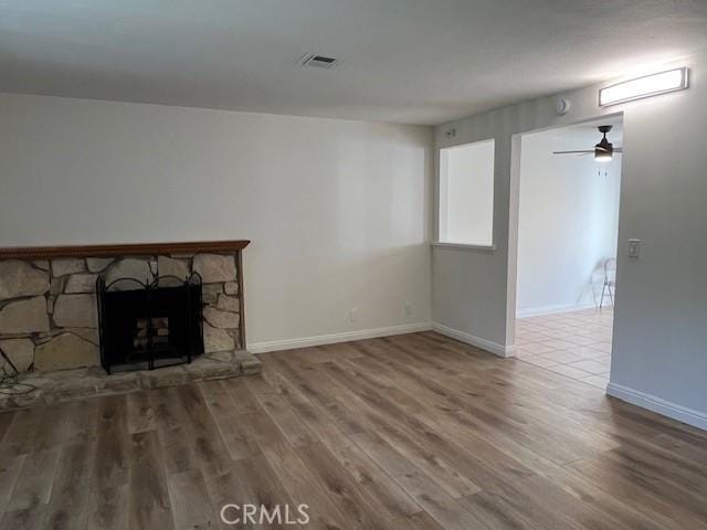 unfurnished living room featuring hardwood / wood-style floors, a fireplace, and ceiling fan