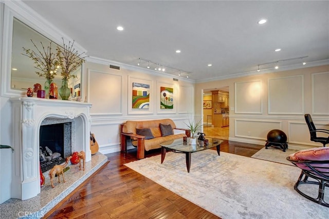 living room with a fireplace, ornamental molding, rail lighting, and wood-type flooring