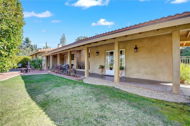 back of property with a yard and a patio area